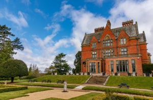 沃里克Wroxall Abbey Hotel的一座大型红砖建筑,有草地庭院