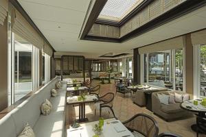 曼谷Capella Bangkok的餐厅设有桌子、沙发和窗户。