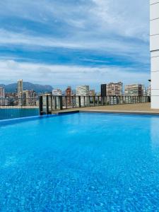 贝尼多姆GEMELOS Levante beach apartments的一座大型蓝色游泳池,位于一座建筑的顶部