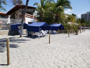 圣玛尔塔Hospedaje Villa Naloy的沙滩上沙滩上摆放着蓝色遮阳伞和椅子