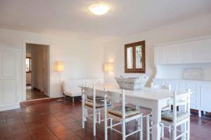罗通多港Residenza Costasmeraldina的白色的用餐室配有白色的桌椅