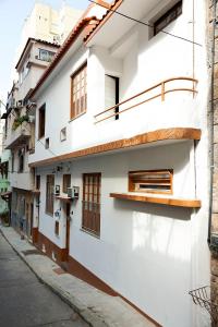 里约热内卢Casa Saga - All Suites的白色的建筑,在街上设有木窗
