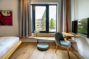 柏林numa l Drift Rooms & Apartments的一间卧室配有书桌、床和窗户。