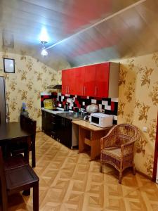 克洛佩夫尼茨基Мини-отель的厨房配有红色橱柜和桌椅