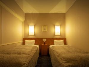 盛冈盛冈爱斯酒店的一间设有两张床的房间和墙上的两盏灯