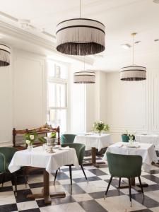 San Esteban de PraviaGran hotel Brillante的餐厅设有桌子、绿色椅子和吊灯