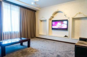阿拉木图皇宫酒店的一间酒店客房,配有桌子和墙上的电视