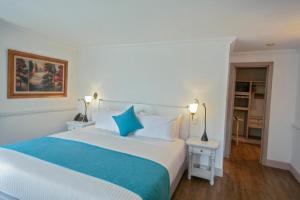波哥大Hotel Vintage的卧室配有带蓝色枕头的大型白色床