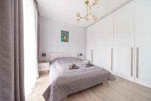 尤尔马拉Brand new apartment with terrace near the sea的白色卧室配有一张床和一个吊灯