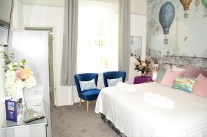 佩恩顿圣埃德蒙兹宾馆的一间卧室配有一张床和两张蓝色椅子