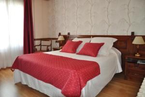 坎普罗东Hotel Edelweiss的一间卧室配有一张带红色枕头的大床