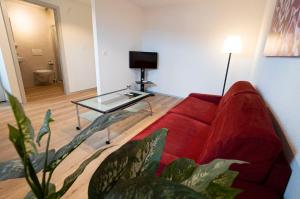 赛尼厄莱吉耶Hôtel Bellavista "Bellevue"的客厅配有红色的沙发和玻璃桌