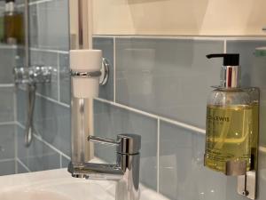 霍舍姆Lancasters Cottage的浴室盥洗盆和镜子旁的肥皂饮水机