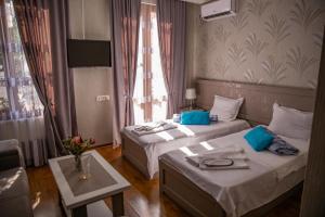 第比利斯Family Hotel Kolorit Old Tbilisi的酒店客房设有两张床和一张桌子。