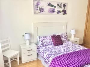 布里拉蒂卡波Piso céntrico próximo a la playa的一间卧室配有紫色的床和白色椅子