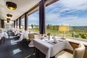 金特斯贝格Panorama Ferien Hotel Harz的餐厅设有白色的桌椅和大窗户。