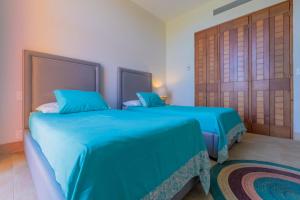 女人岛Isla Sunset Rentals at Sotavento的配有蓝色床单的客房内的两张床