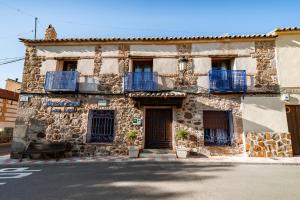拉耶斯Casa Rural Álamo Grande的一座古老的石头建筑,街道上设有蓝色的阳台