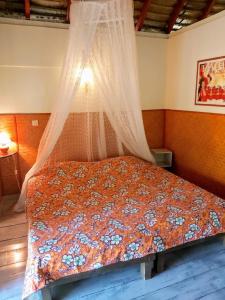 法勒HUAHINE - Bungalow Vanille 2p的卧室内的一张带天蓬的床