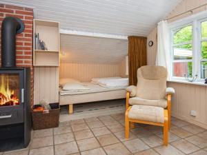 海默特4 person holiday home in Hemmet的一间卧室配有一张床、一把椅子和一个壁炉