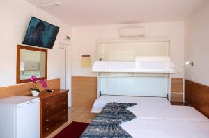 卡什塔涅拉德佩拉Praia das Rocas Bungalows的卧室配有白色的床和带微波炉的梳妆台。