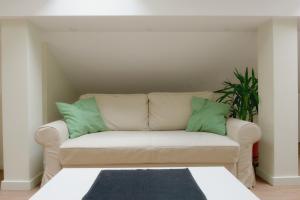 贝尔格莱德VUKAJLO apartment Belgrade的一张带两个绿色枕头的白色沙发