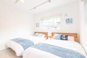 白滨West Coast Villa Shirahama的白色墙壁客房中的两张单人床