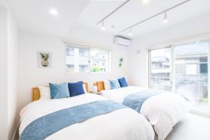 白滨West Coast Villa Shirahama的白色客房的两张床,设有窗户