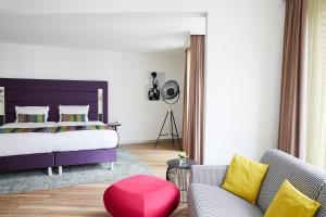 杜塞尔多夫杜塞尔多夫胜利广场靛蓝酒店的一间卧室设有一张大床和一张红色凳子