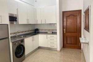 拉雷斯廷加Kalma IV的厨房配有白色橱柜和洗衣机。