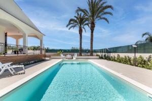锡拉库扎House&Villas - Due Palme的棕榈树房子后院的游泳池