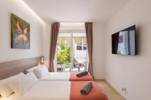 马斯帕洛马斯Villa Deluxe Suites Maspalomas的酒店客房设有两张床和电视。