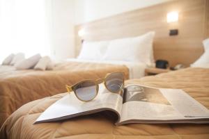 里米尼Hotel Costazzurra by Interlux的坐在书上躺在床上的眼镜