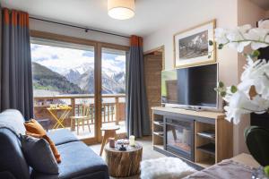 莱德萨阿尔卑斯Résidence Club MMV Les Clarines的带沙发和电视的客厅以及阳台。