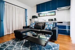 白马村Sali's House的客厅配有黑色真皮沙发和蓝色橱柜