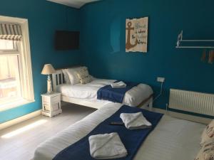 布莱克浦The Glenroy Guest House的蓝色墙壁客房的两张床