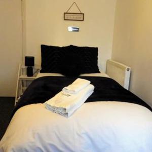 霍尔斯沃西Kings Arms Hotel的一间卧室配有一张带白色床单和黑色枕头的床。