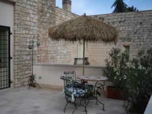 卡萨诺德莱穆尔杰Casarosa B&B de Charme的庭院配有桌椅和草伞。