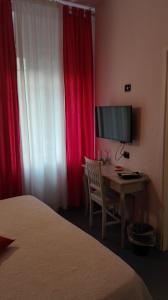 佛罗伦萨坎托戴米勒旅馆的一间卧室配有一张桌子、一台电视和红色窗帘