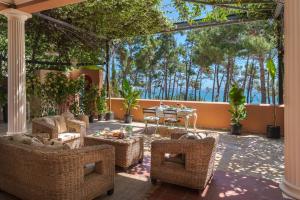 斯卡拉Scorpios Mansion / Downtown Skala / Seaside的庭院设有藤椅和桌子,树木繁茂。