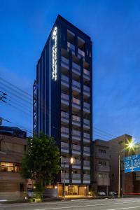 广岛HOTEL SUITE HIROSHIMA HAKUSHIMA的夜幕降临的城市街道上一座高大的黑色建筑