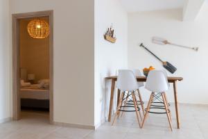 埃尔米奥尼Grand Bleu Apartments & Villas的一间带桌子和两个白色凳子的用餐室