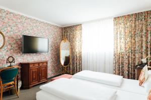 威斯巴登Das Kleine Hotel in ruhiger Stadtlage的酒店客房设有两张床和一台墙上的电视。