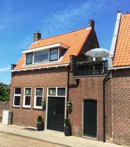 滨海卡特韦克Vakantiehuis De Oude Bakkerij的一座砖屋,拥有橙色的屋顶和一个阳台