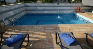 帕拉利亚卡泰里尼斯NABRO Resort的一个带两把椅子的游泳池和一个喷泉