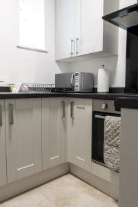 韦克菲尔德2D SPV Double En-suite Room的厨房配有白色橱柜和黑色台面