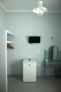 帕罗奇亚Passos Rooms的客房设有小冰箱和墙上的电视。