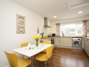 BryngwranBwthyn Tyn y Coed的厨房配有白色的桌子和黄色的椅子