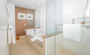 檀香山Kaimana Beach Hotel的一间带水槽和玻璃淋浴的浴室