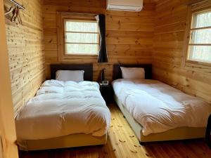 原村Haramura CAFE Lodge - Vacation STAY 33104v的配有木墙和窗户的客房内的两张床
